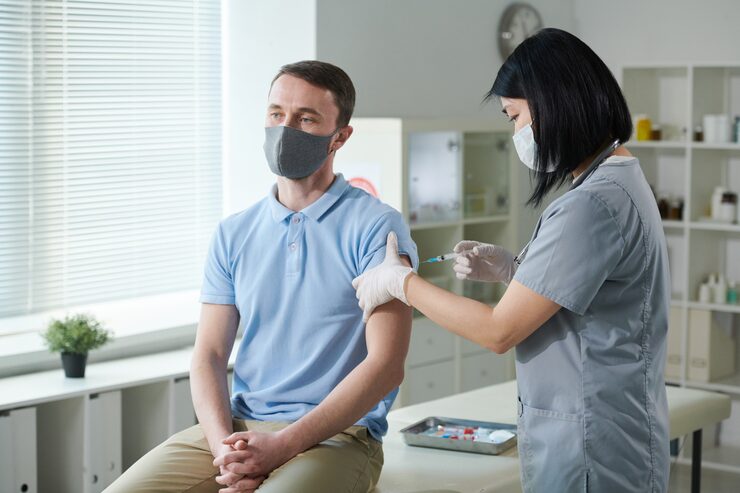 brunette nurse asian ethnicity uniform protective mask vaccinating young man sitting medical office modern clinics 274679 19811